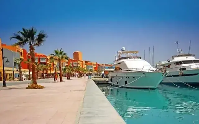 Iates atracados na Marina de Hurghada, com palmeiras e prédios coloridos