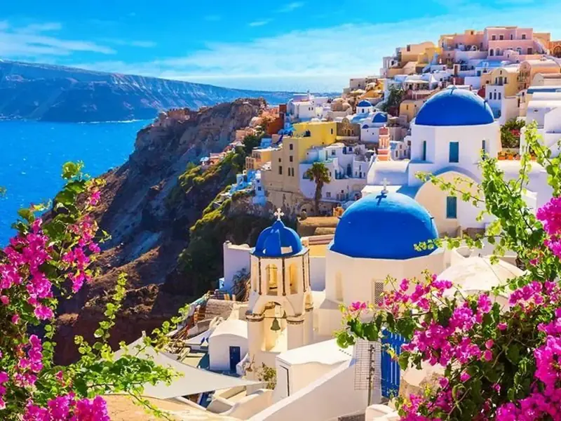 Vila de Oia com cúpulas azuis e flores, em Santorini, Grécia