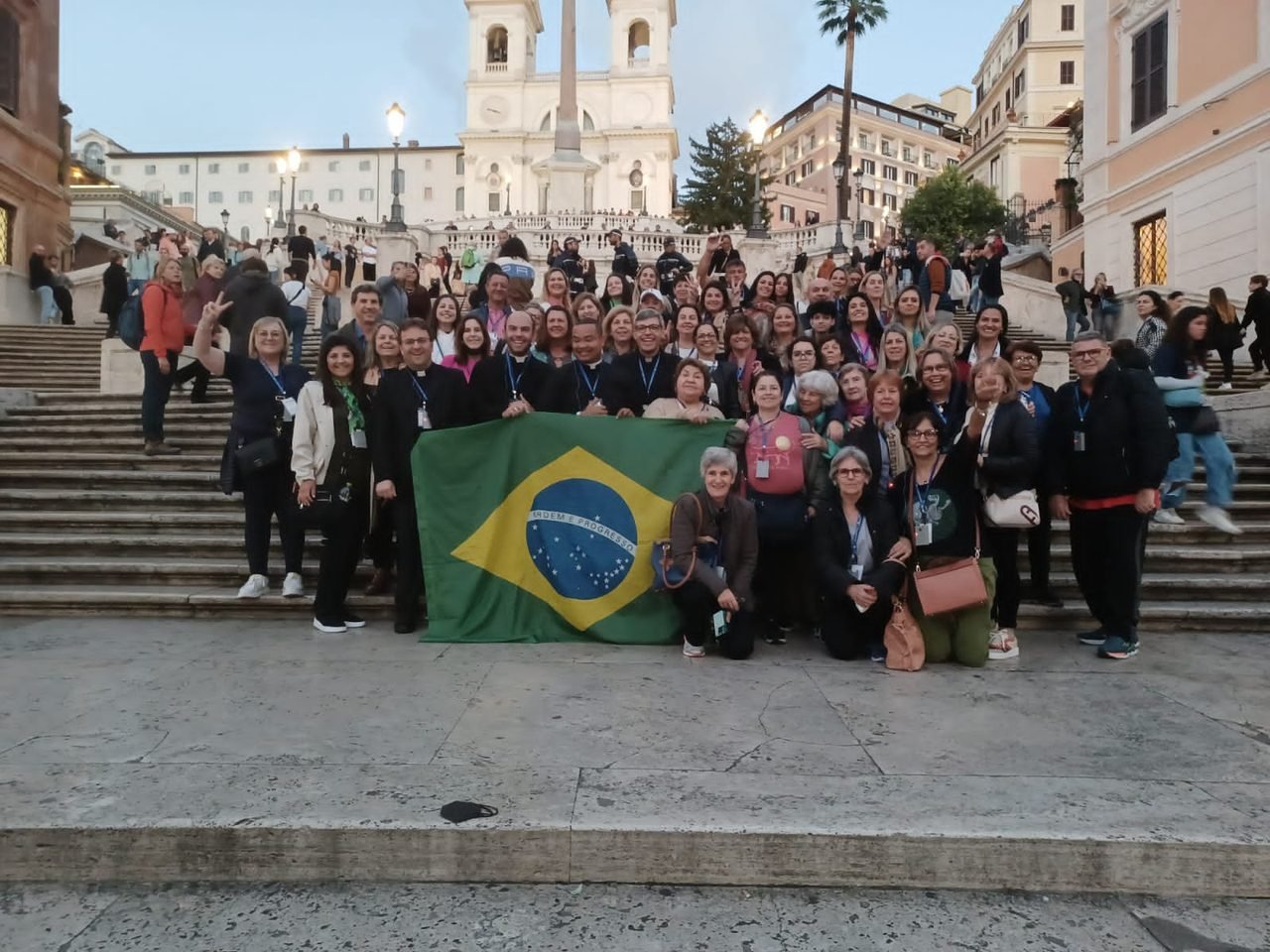 Grupo de clientes da EGP Viagens com a bandeira do Brasil na Escadaria da Piazza di Spagna, em Roma