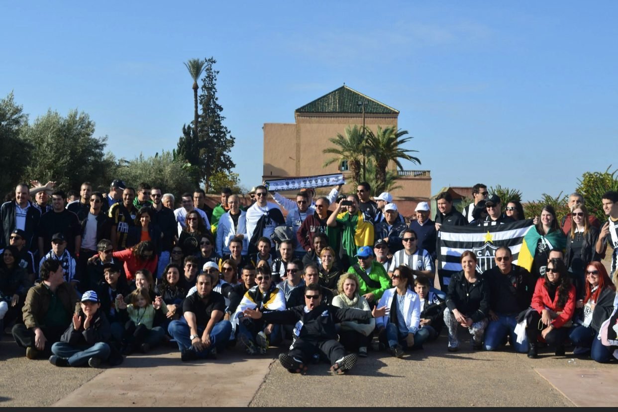 Grupo de clientes da EGP Viagens em um sítio histórico, segurando bandeiras durante excursão