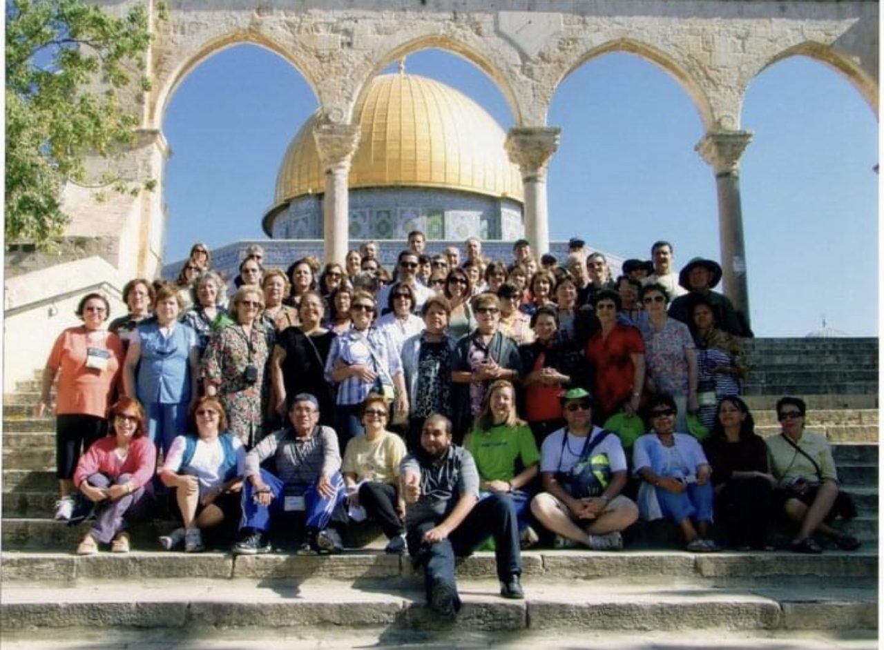 Grupo de clientes da EGP Viagens em frente a um monumento histórico com arcos, durante excursão