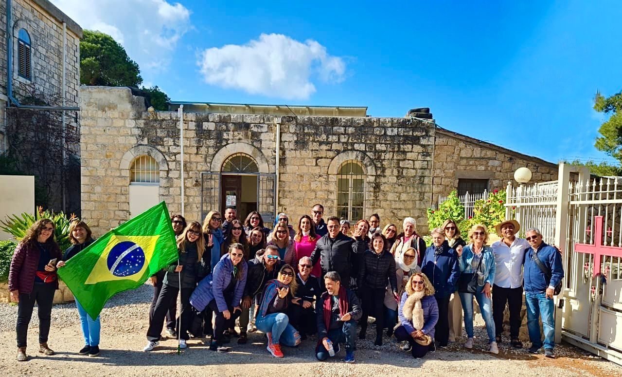 Grupo de clientes da EGP Viagens posando com a bandeira do Brasil durante excursão