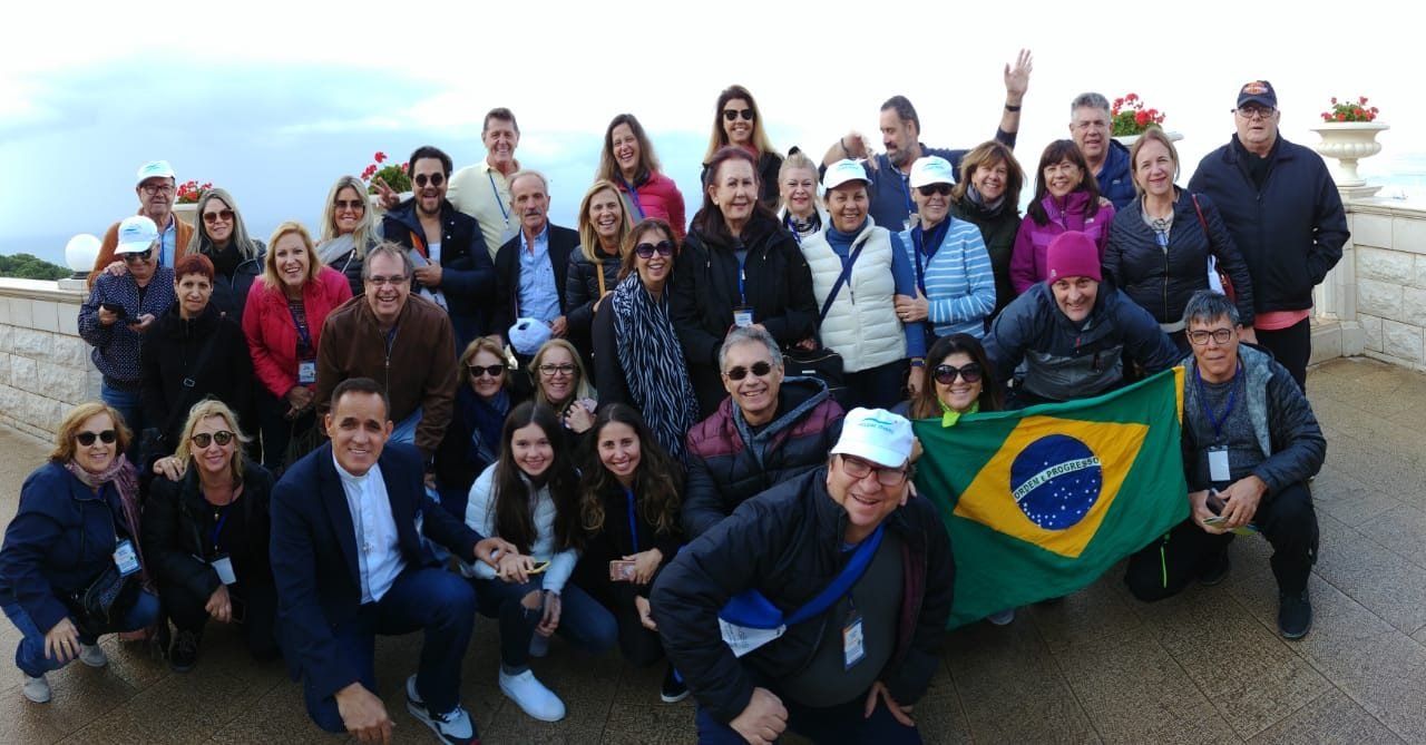 Grupo de clientes da EGP Viagens em recepção oficial durante viagem, com bandeira do Brasil