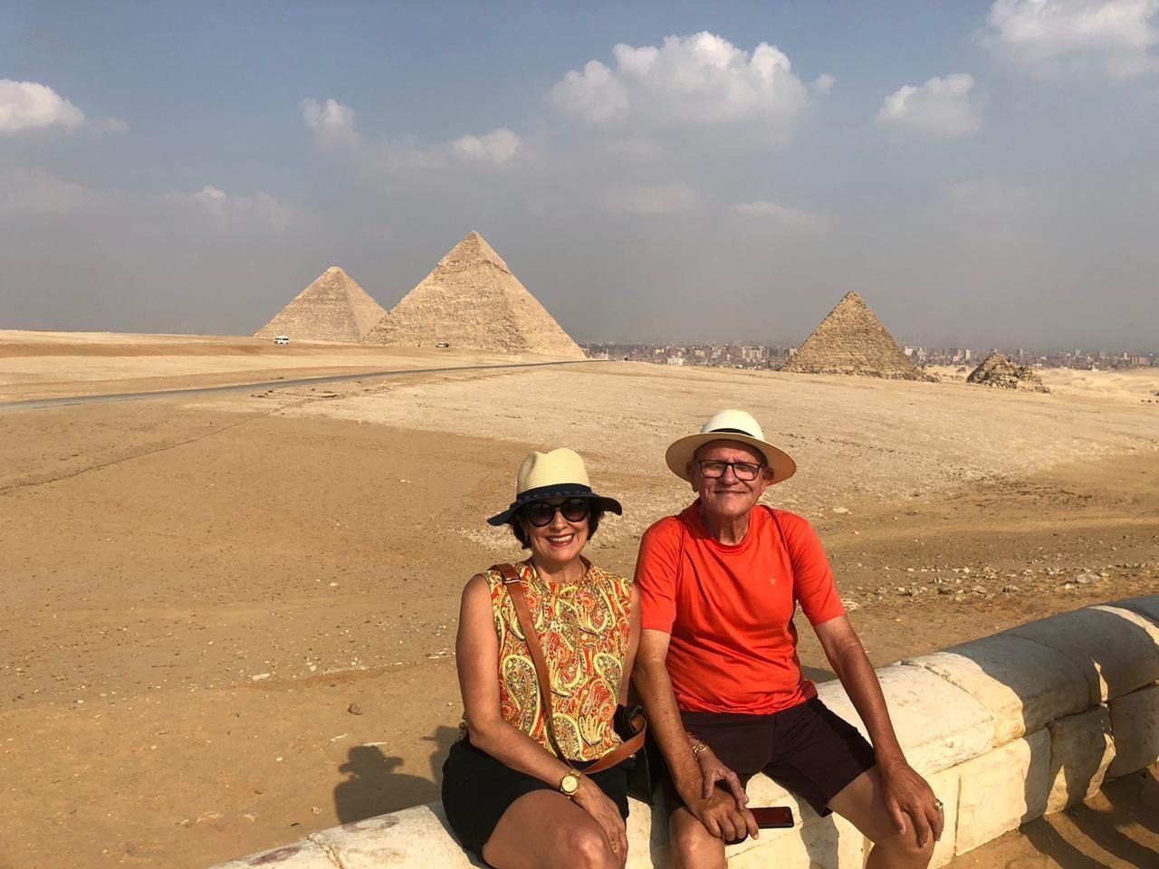 Casal de clientes da EGP Viagens sorrindo em frente às Pirâmides de Gizé, no Egito